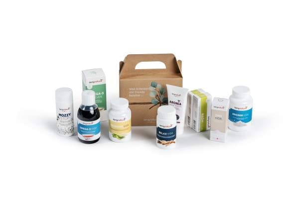 Auf weißem Hintergrund sind verschiedene Nahrungsergänzungsmittel in Flaschen, Schachteln und einem braunen Karton angeordnet, jeweils mit unterschiedlich farbigen Etiketten und Produktnamen, darunter auch Vitamine.